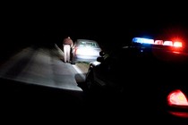 A photo of a police car behind a car that was pulled over at night