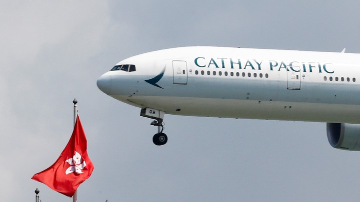 A Cathay Pacific plane hovers beside the flag of Hong Kong.