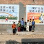 A group of young boys stands close to two large posters extolling the one-child policy.
