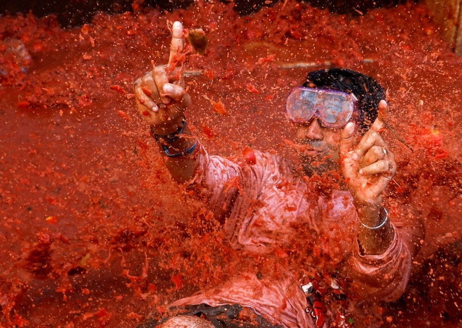 A person wearing a diving mask splashes in tomato pulp.