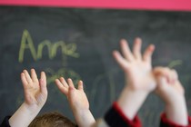 Children's hands in the air in front of a chalkboard