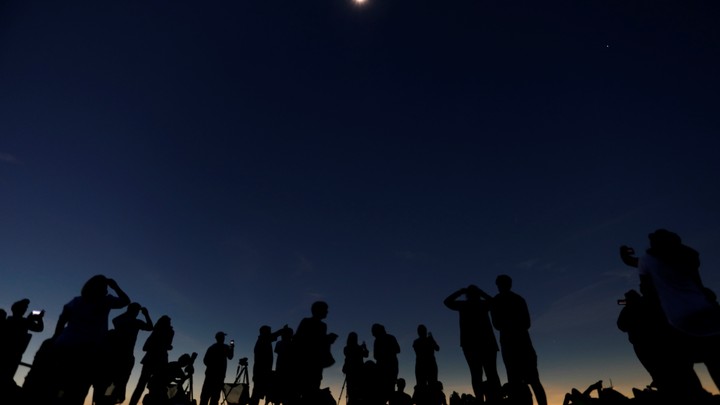 A group of people watches a solar eclipse.