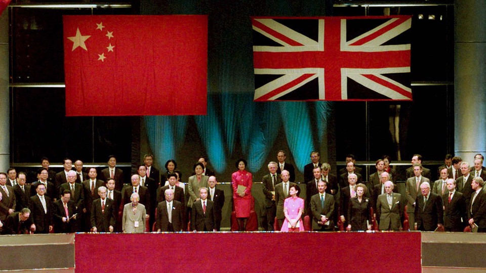 Chinese and British leaders stand beneath the flags of China and the United Kingdom.