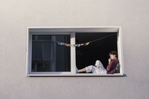 A woman lounges in the window of an apartment building