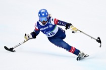 A para-alpine skier using outrigger skis leans and makes a tight turn.