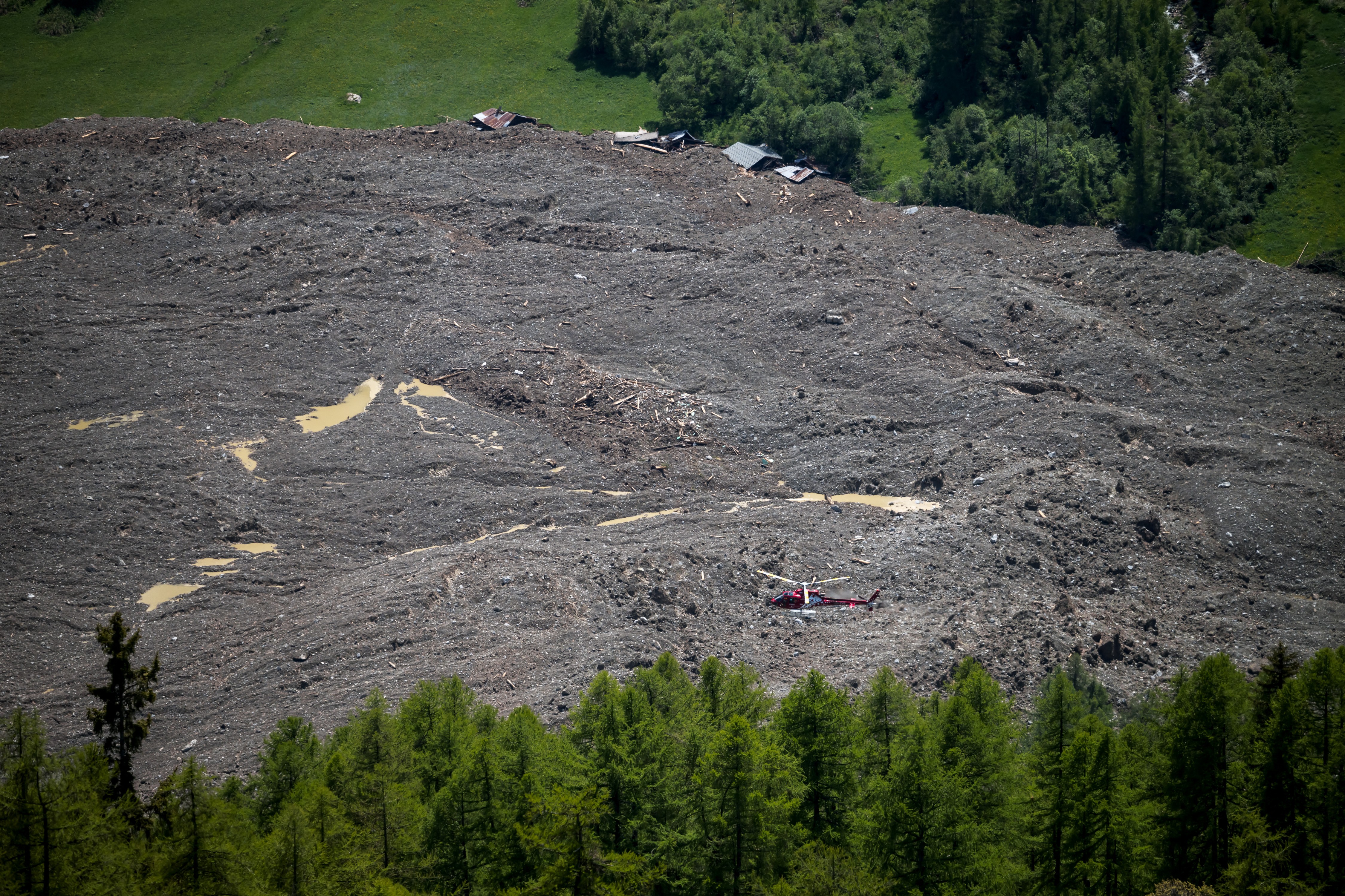 A helicopter flies above a recent landslide.