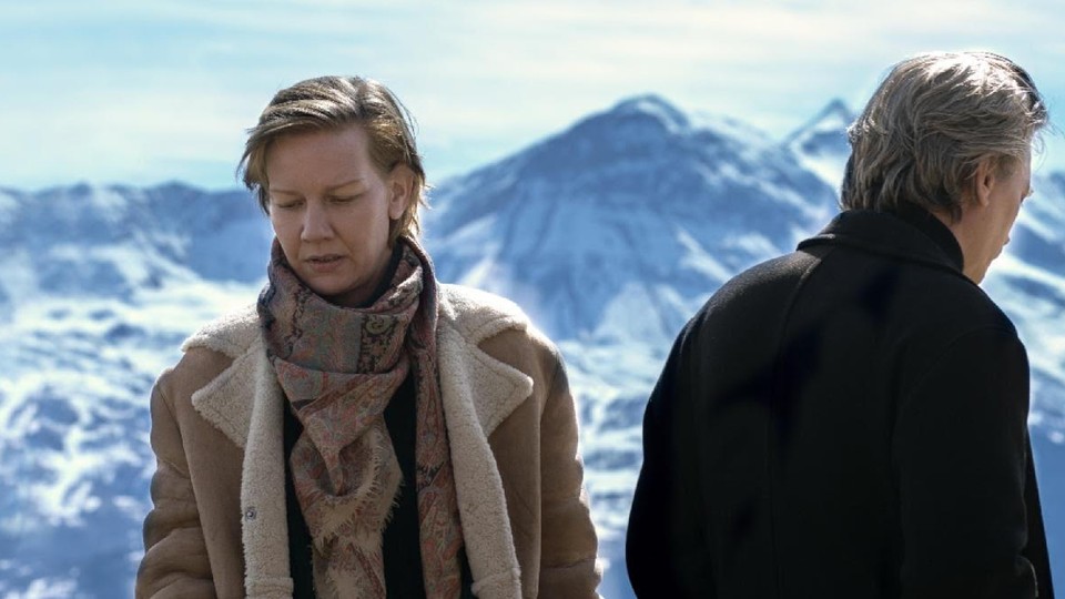 Sandra Hüller and Samuel Theis looking in opposite directions against a backdrop of snowy mountains