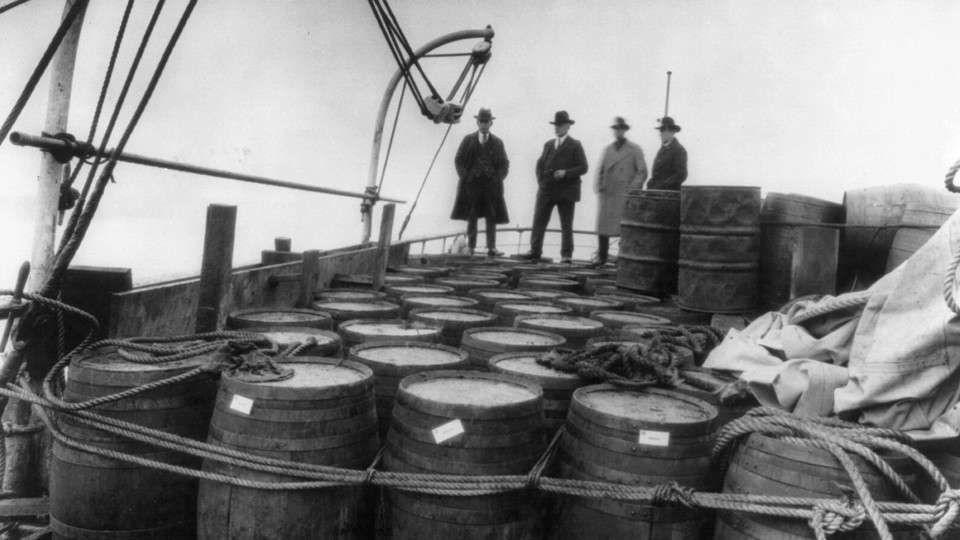 Prohibition agents examining barrels on boat, c. 1925.