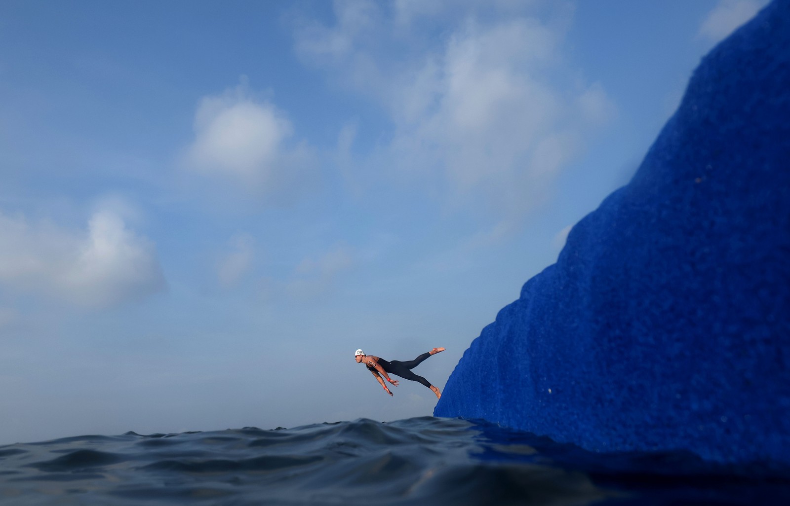 A person dives from a floating dock into the water for a swimming race.