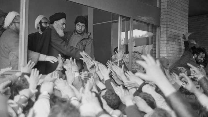 Ayatollah Ruhollah Khomeini greets a crowd of people waving their hands at him at Tehran University in 1979.