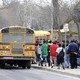 Students walk alongside school buses.
