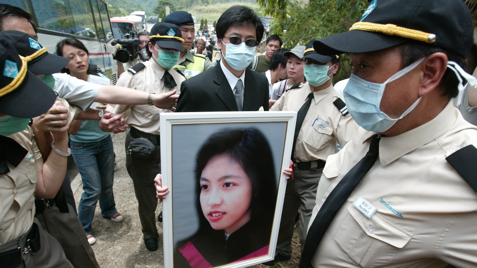 The burial of Dr Joanna Tse Yuen-Man, who died of SARS, at Gallant Garden, Wo Hop Shek. A relative is holding her portrait.