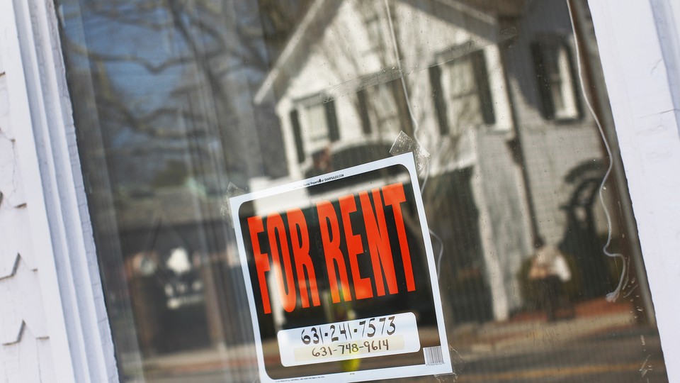 A "for rent" sign hangs in the window of a home.