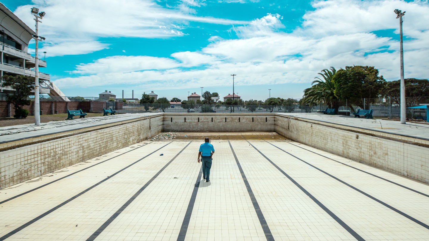 A man walks along the bottom of an empty public swimming pool near Cape Town.