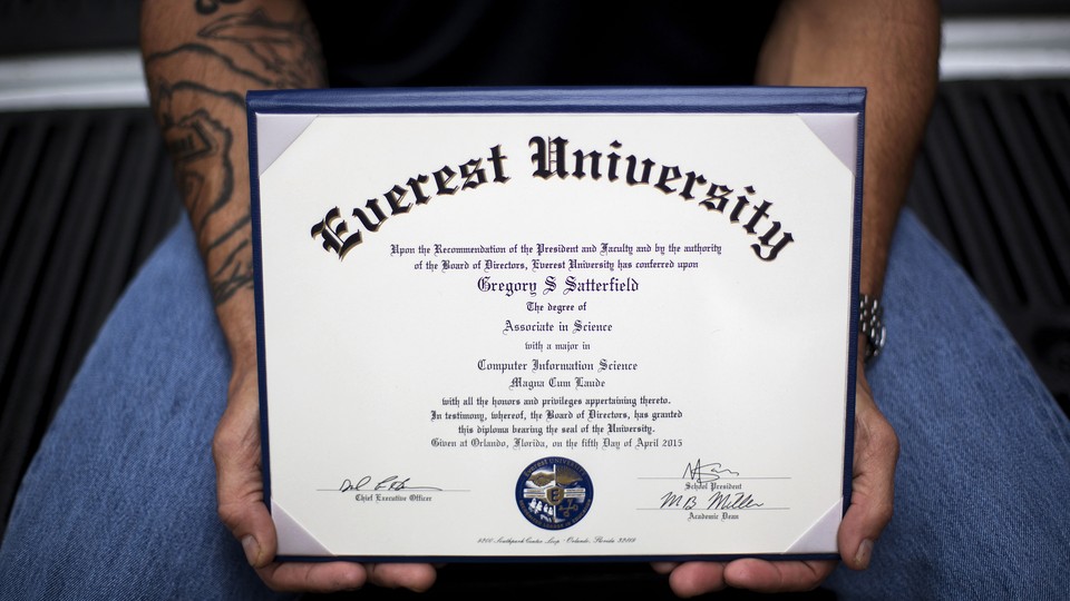 A man with tattoos on his arm holds a diploma.