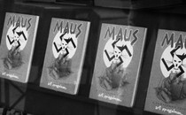 A black and white image of four 'Maus' books on a shelf. The cover depicts two mice huddled together under a swastika that bears the image of a cat drawn to look like Hitler
