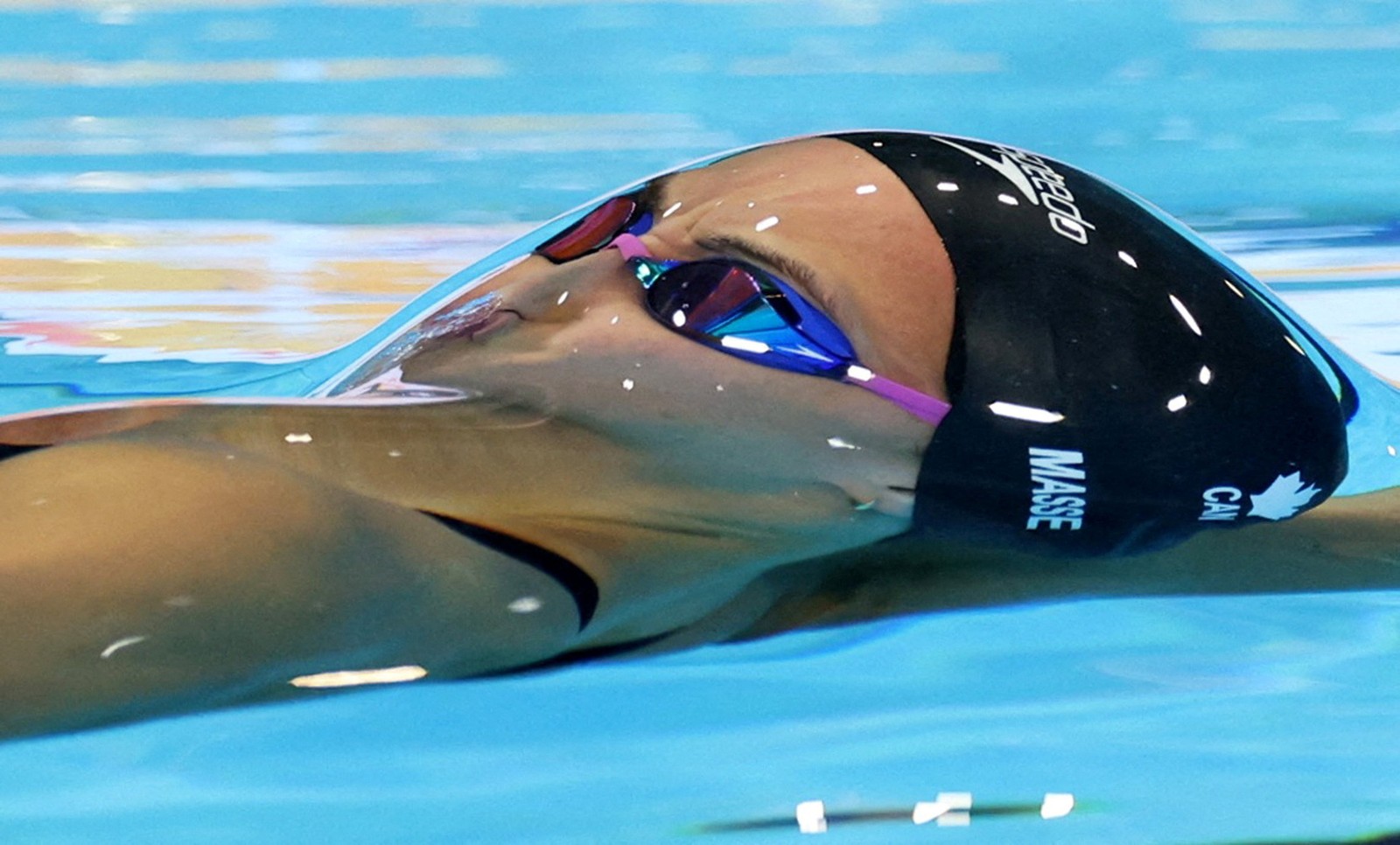A close view of a swimmer's head during a race, seen just beneath the waters surface, slightly distorted by a lensing effect.