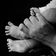 an adult's hand holds up a baby's feet, in greyscale