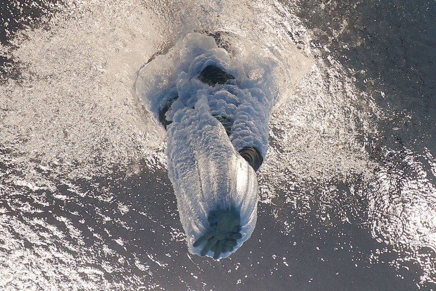 An underwater view of a diver plunging into a pool with hands outstretched