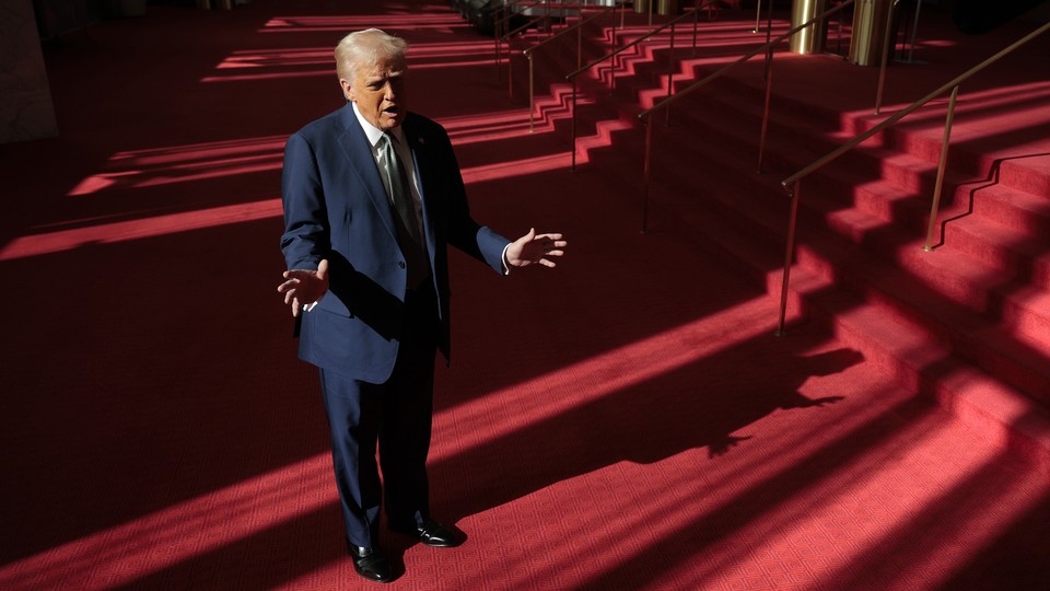 Donald Trump stands with his arms outreached on the red carpeted walkway in the Kennedy Center