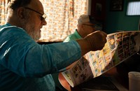 A man reads The Hawk Eye newspaper in a diner.