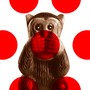 A statuette of a monkey covering its mouth, overlaid with red polka dots
