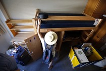 A student sets up her twin-sized bed and arranges other items in her dormitory.