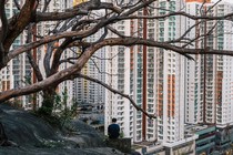 A man sits on a hill overlooking a residential estate in Hong Kong