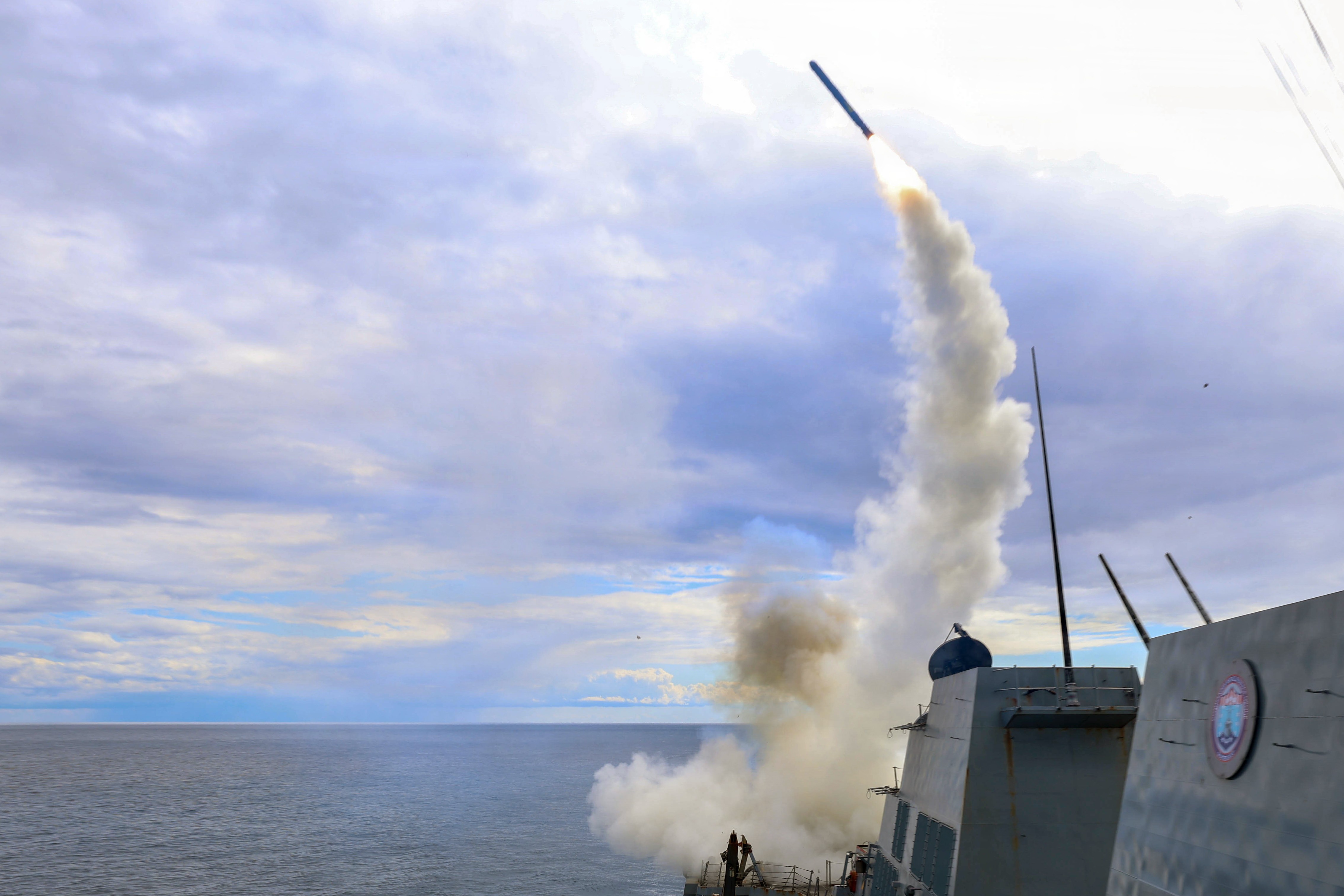 A missile launches from the deck of a ship.