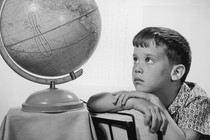 A young man stares at an old-fashioned globe