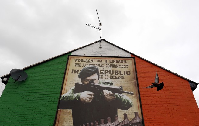 A pigeon flies past a mural supporting the Irish Republican Army in Belfast.