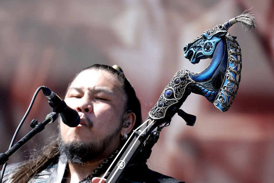 A performer sings while playing an ornate traditional stringed instrument.