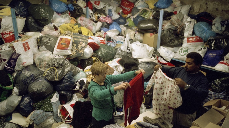 People sorting through enormous piles of recycled clothing.