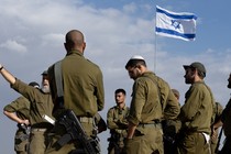 Soldiers gather around an Israeli flag as they receive a briefing near the border with Gaza.