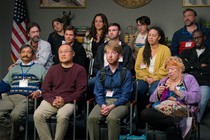 The cast of "Jury Duty" sitting in three rows of chairs and facing a camera for a debrief