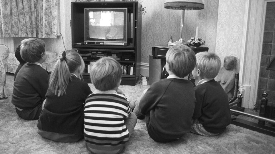 A black-and-white photo of children watching television