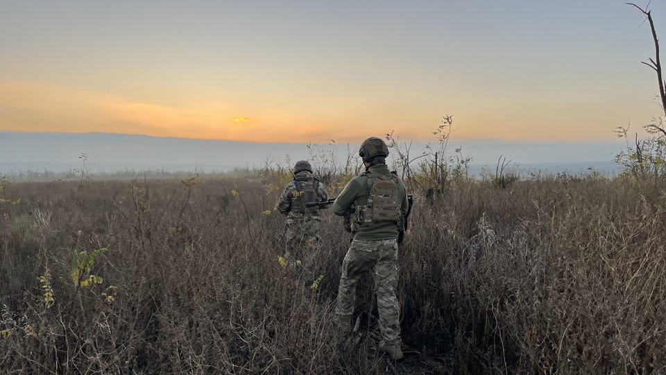 Two soldiers walk in a field at sunrise