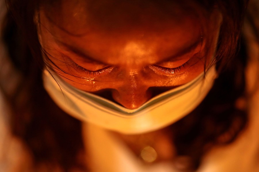 A close view of a person weeping while wearing a face mask.