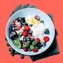 A white bowl with yogurt, blueberries, raspberries