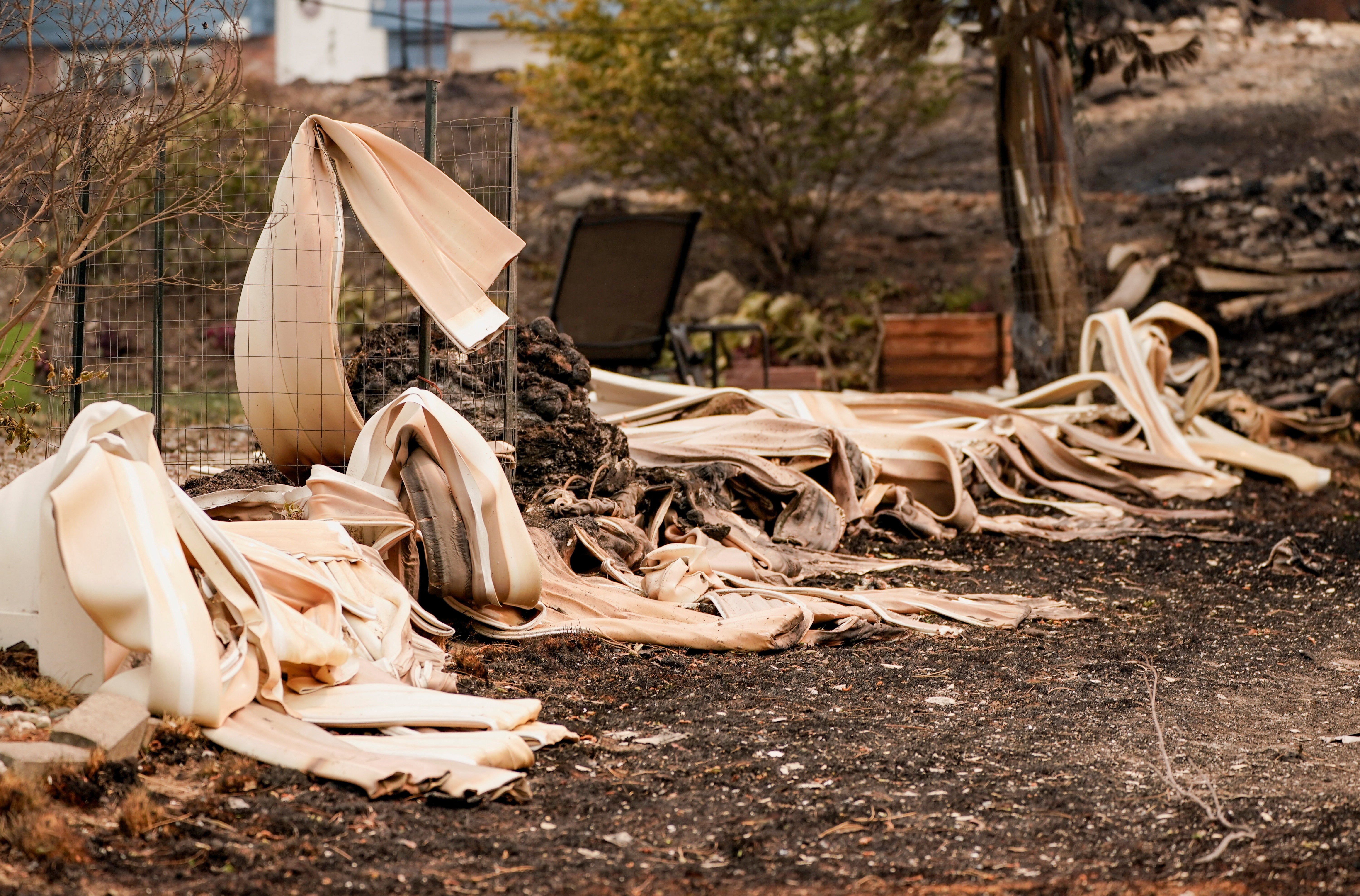 Melted siding lies outside a property damaged by a wildfire.