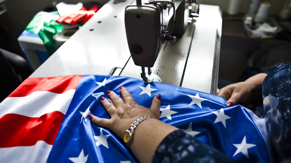 A factory worker sews an American flag