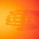 A burst of orange light with the faint outline of hands around the light burst