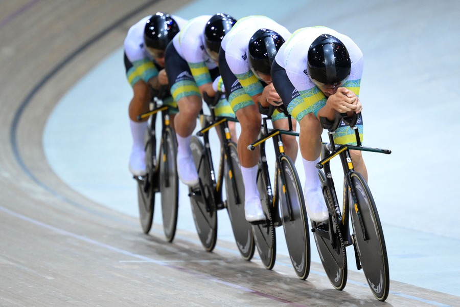 A team of four professional cyclists ride in a very close line.