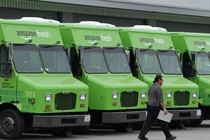 Amazon Fresh delivery vans are lined up outside an Amazon warehouse