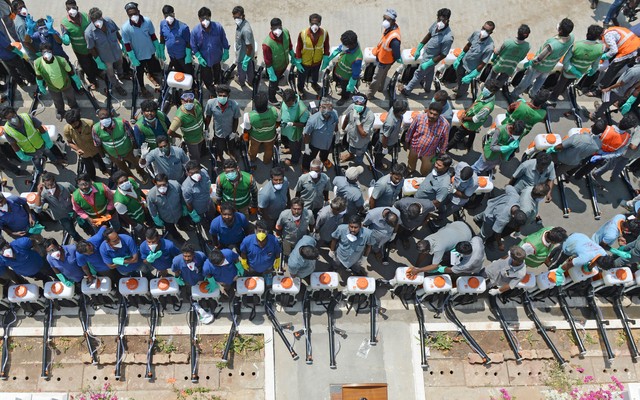 Health workers wearing facemasks amid concerns over the spread of the COVID-19 novel coronavirus, stand as they wait to spray disinfectant at the corporation office in Chennai on March 20, 2020.
