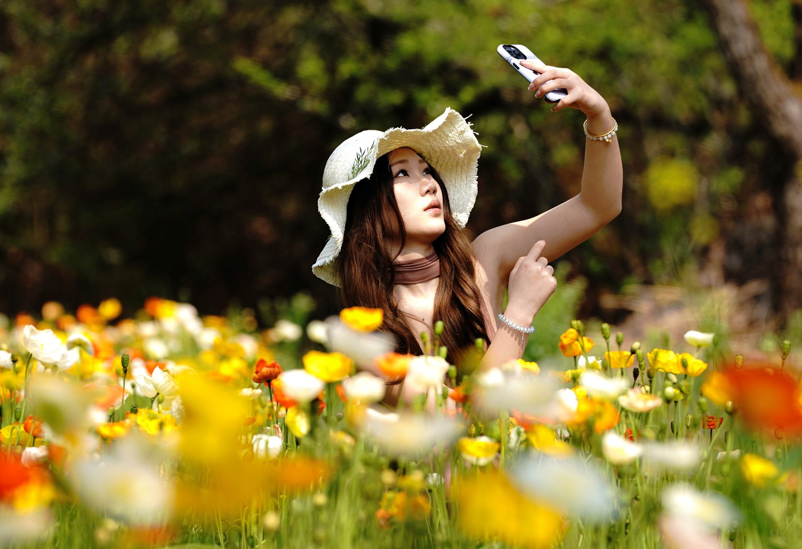 A visitor takes selfies in a field of flowers.