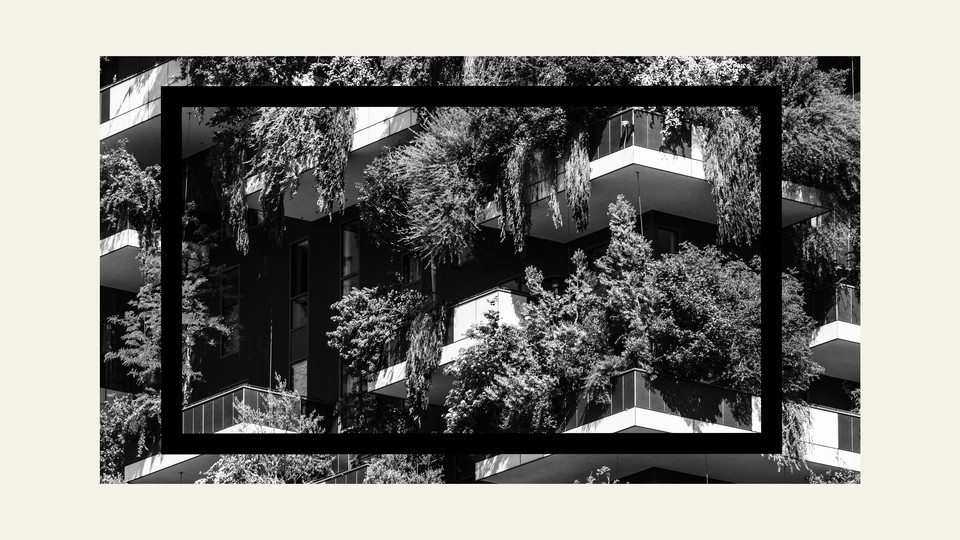 A black-and-white image of the exterior of an apartment building with balconies and greenery