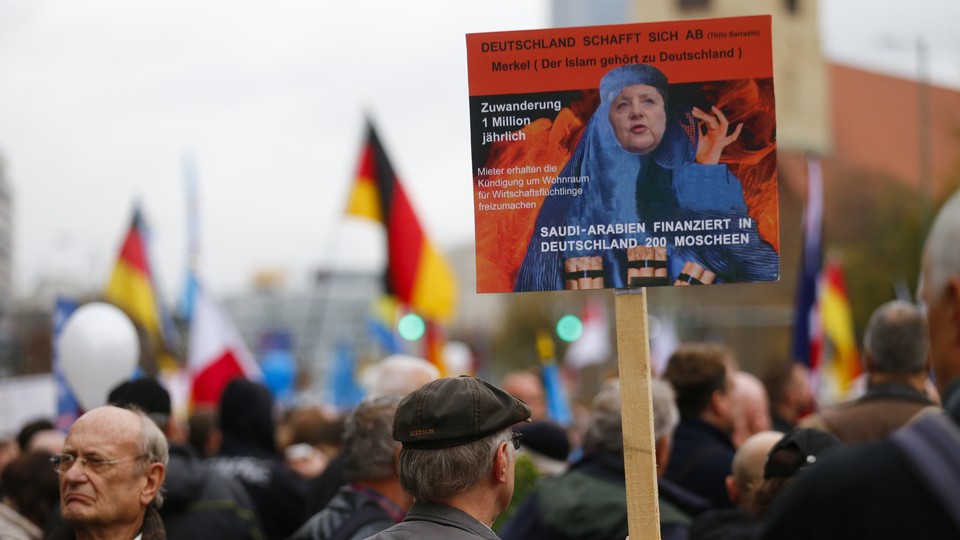 A supporter of the far-right German party AfD holds an anti-Islam, anti-Merkel placard at a 2015 rally.