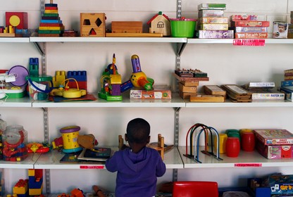 A kid stands in front of shelves of toys