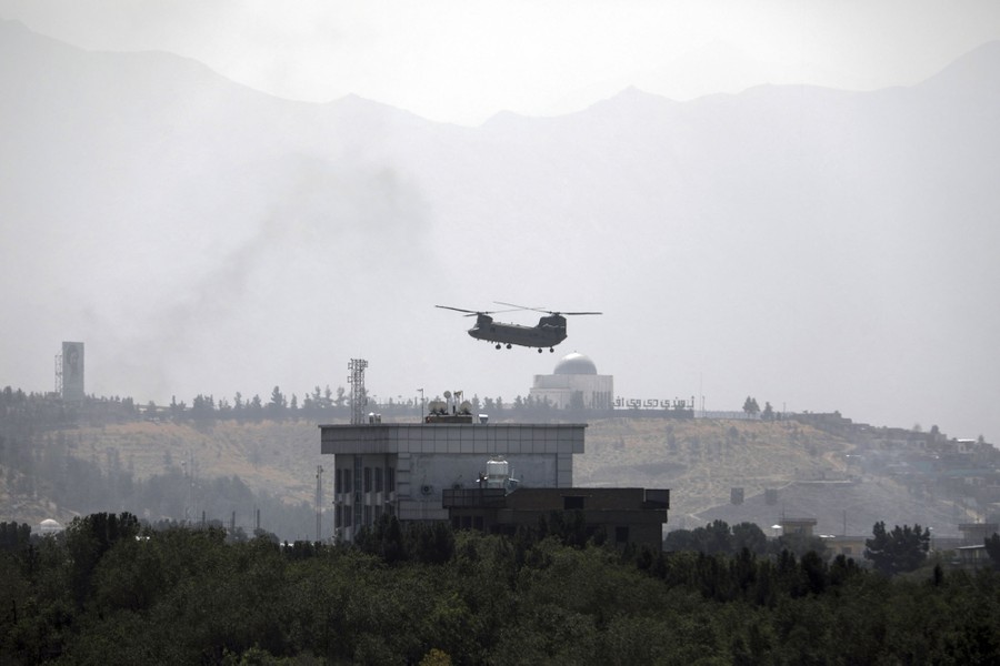 A helicopter flies low above a building.